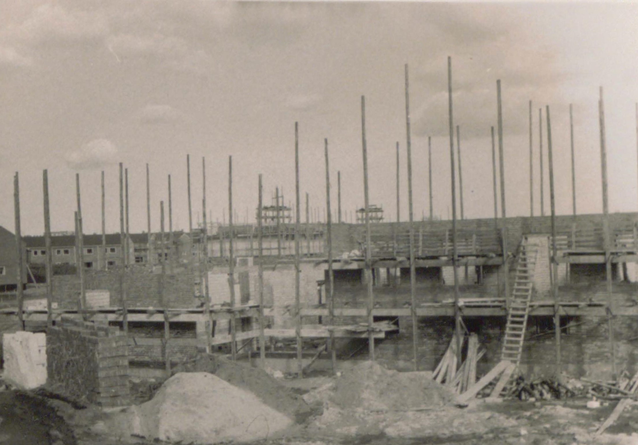Aufnahme von der Baustelle in Hamburg-Langenhorn: Baumaterialien liegen umher, Holzpfähle stecken in der Erde.