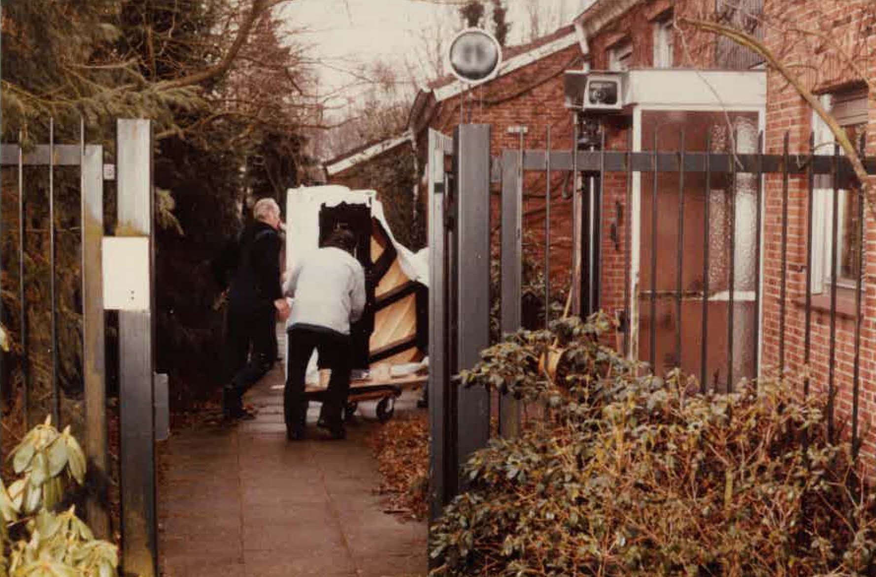Menschen rollen einen Flügel in das Wohnhaus der Familie Schmidt.